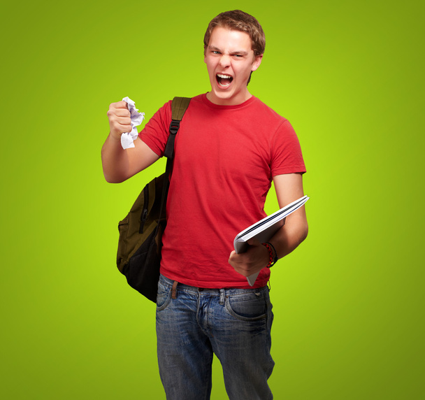 jonge boos student man Afbramen van een blad over groene achtergrond - Foto, afbeelding