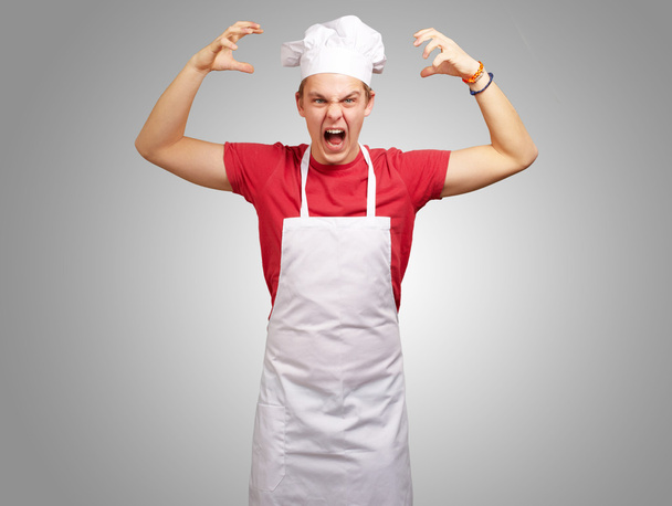 Portrét mladého kuchaře muž nosí zástěru dělat agresivní gestur - Fotografie, Obrázek