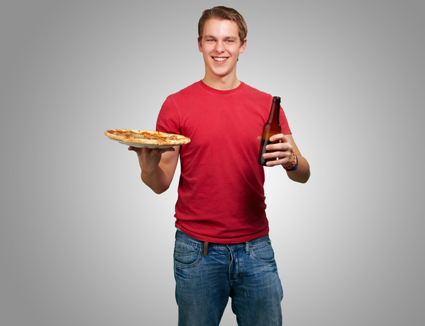 Portrait de jeune homme tenant pizza et bière sur fond gris
 - Photo, image
