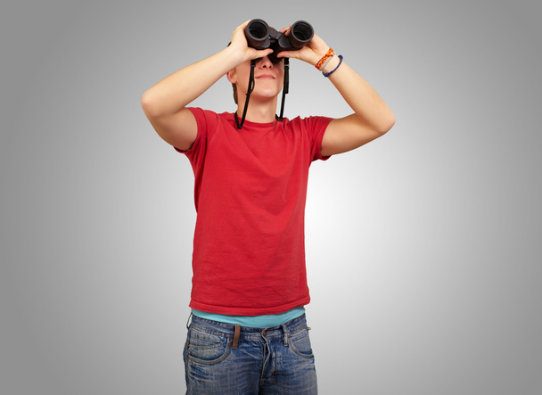 Portret van een jonge man met een verrekijker over grijze achtergrond - Foto, afbeelding