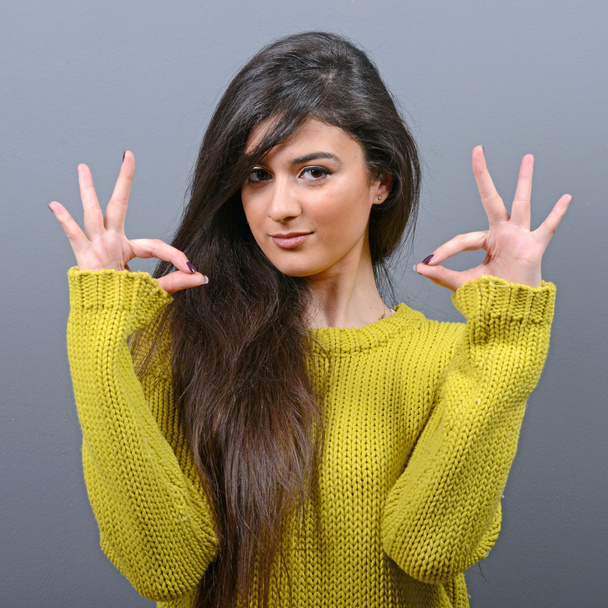 Portrait of happy woman showing ok sign against gray background - Photo, image