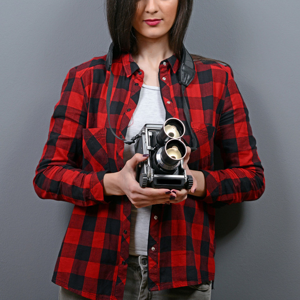 Portrait of hipster girl with retro camera against gray backgrou - Фото, изображение