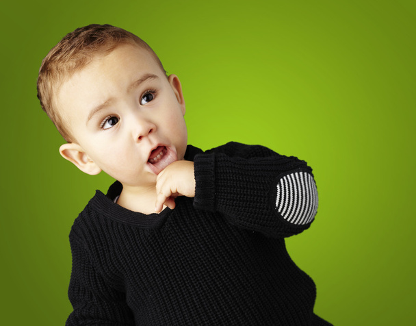 Porträt eines entzückenden, nachdenklichen Kindes vor grünem Hintergrund - Foto, Bild