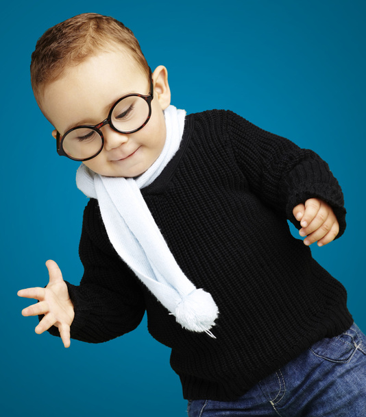Portrait of kid wearing glasses looking down against a blue back - Photo, image