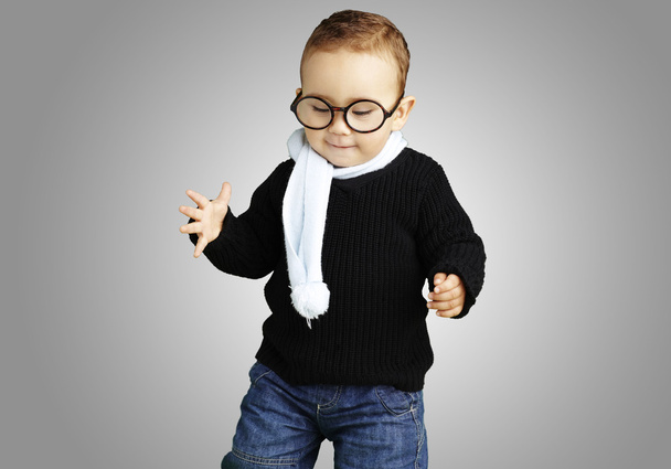 Portrait d'enfant portant des lunettes regardant vers le bas contre un dos gris
 - Photo, image