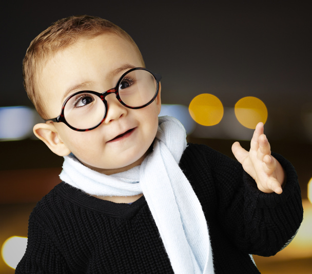Πορτρέτο του αξιολάτρευτο παιδί φορώντας γυαλιά χειρονομώ αμφιβολία στο city - Φωτογραφία, εικόνα