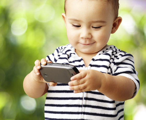 Portrait d'enfant drôle jouant avec mobile au parc
 - Photo, image