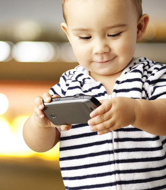 Portrait d'enfant drôle jouant avec mobile contre un bac abstrait
 - Photo, image