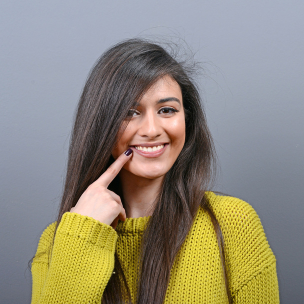 Portrait of woman pointing at her healthy white teeth against gr - Photo, image