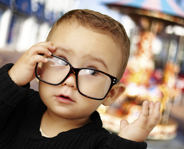 Portrait d'enfant portant des lunettes et levant les yeux contre une carouse
 - Photo, image
