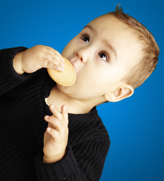 青い背景の上にビスケットを食べる子供の肖像画 - 写真・画像