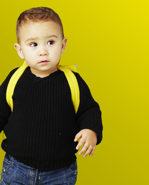 Portrait of adorable kid carrying yellow backpack over yellow ba - Фото, изображение