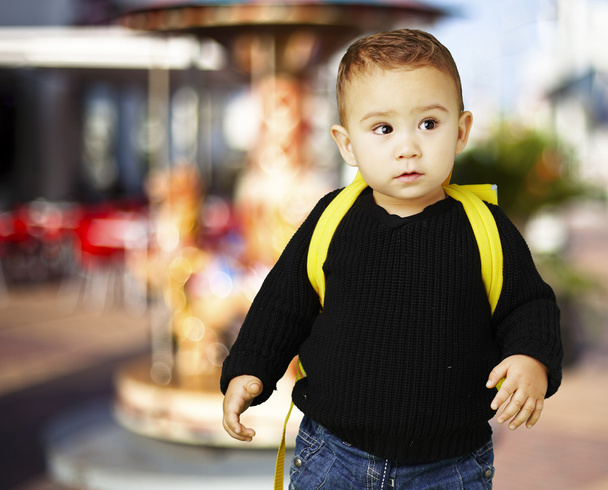 Портрет очаровательного ребенка, несущего желтый рюкзак против каро
 - Фото, изображение