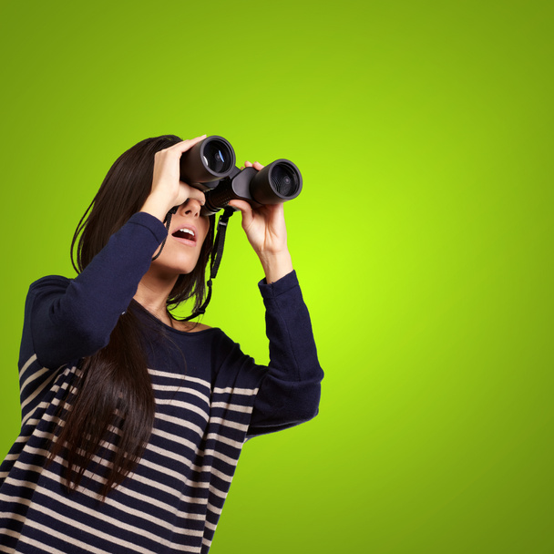 Portrait of young girl looking through a binoculars over green - Photo, Image