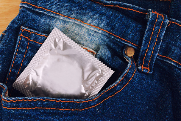 Condoom in de vintage blue jeans zak. Focus op het condoom. - Foto, afbeelding
