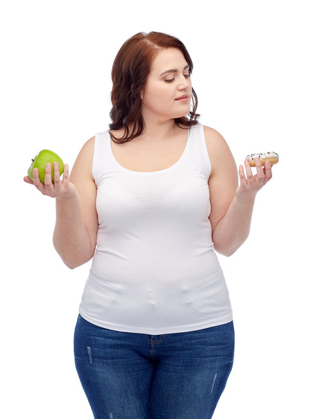 young plus size woman choosing apple or cookie - Foto, afbeelding