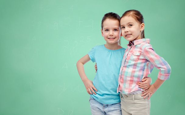 smiling girls hugging over green school board - Valokuva, kuva