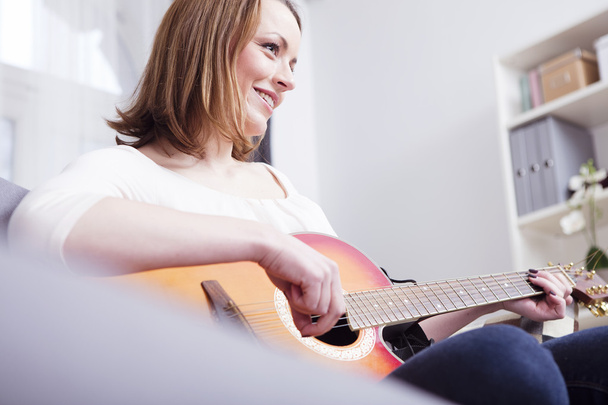young beautiful woman loves music and is playing guitar - Fotografie, Obrázek