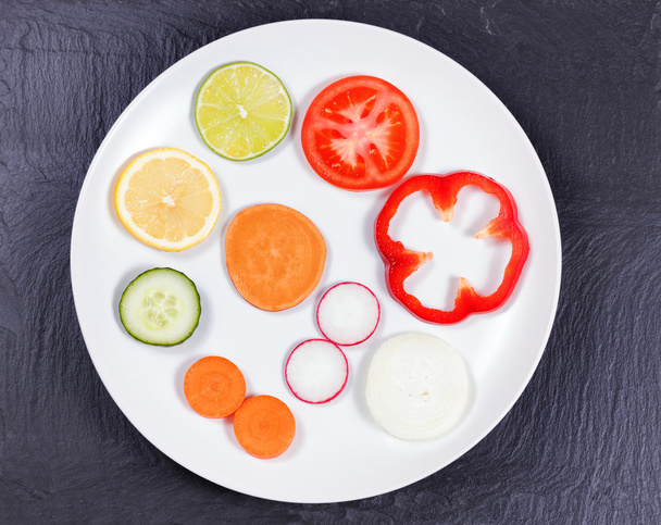 Circle of sliced fruit and vegetables in white plate on natural  - Photo, Image