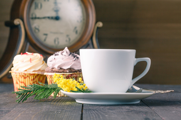 Чашка чая крупным планом и кексы на деревянном столе
 - Фото, изображение