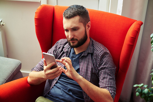 man sitting on the chair and using his smartphone - Photo, Image