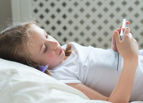 Little girl lying with tablet pc in bed. - Fotó, kép