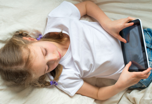 Little girl lying with tablet pc in bed. - Foto, Imagem