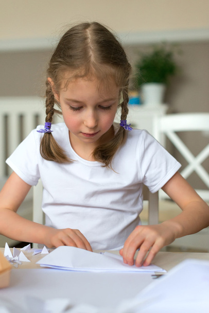 Little girl making paper plane at home. - Photo, image