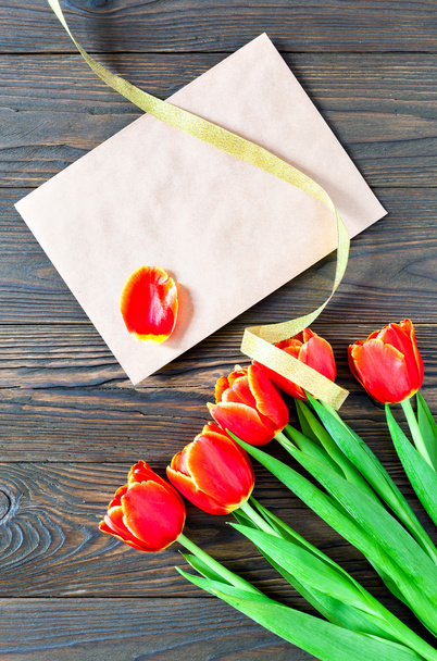 red tulips and kraft envelope on a wooden background - Zdjęcie, obraz