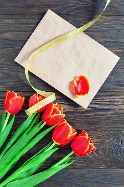 Vörös tulipán és a kraft borítékot egy fából készült háttér - Fotó, kép