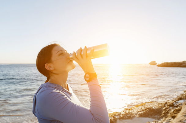 Donna che beve acqua sulla spiaggia
 - Foto, immagini