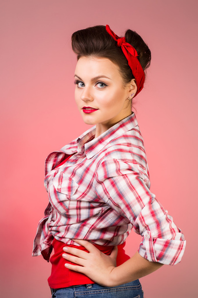 Beautiful young woman with pin-up make-up and hairstyle posing over pink background - Fotoğraf, Görsel