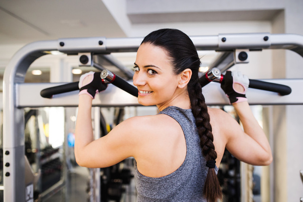 Woman in gym flexing back muscles on cable machine - Foto, imagen