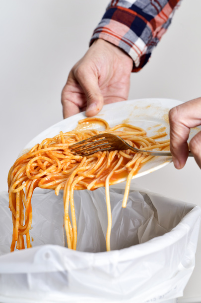 Junger Mann wirft Essensreste in den Mülleimer - Foto, Bild