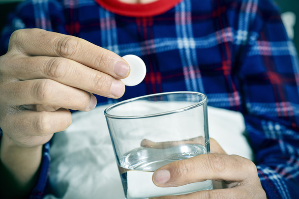 hombre poniendo una tableta efervescente en un vaso con agua
 - Foto, Imagen