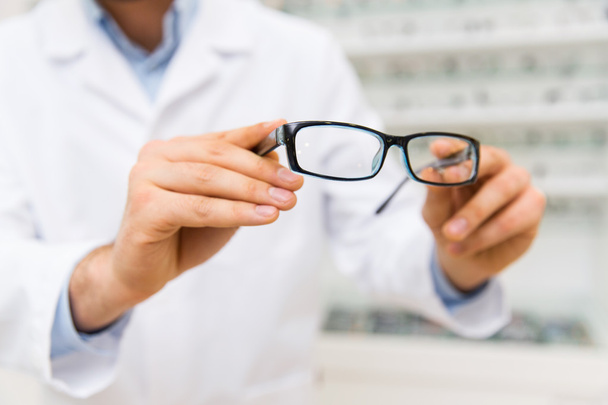 close up of optician with glasses at optics store - Foto, Bild