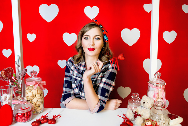 schöne junge Frau im Pin-up-Stil auf rotem Hintergrund mit weißen Herzen - Foto, Bild