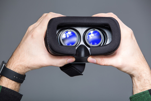 Virtual glasses in man hands over grey - Foto, imagen
