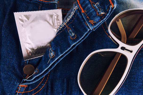Condoom in de vintage blue jeans zak. Focus op het condoom. - Foto, afbeelding
