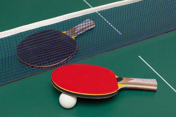 two table tennis racket red and black on a green table - Фото, изображение