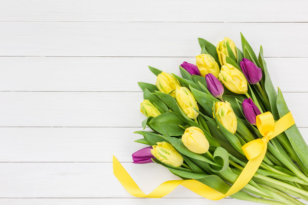 Ramo de tulipanes amarillos y rosados con cinta amarilla sobre fondo de madera blanca, espacio para copiar
 - Foto, Imagen