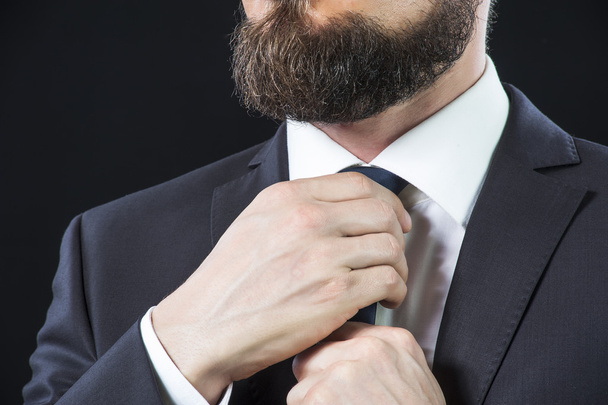 Bearded man tying up his necktie - Foto, afbeelding