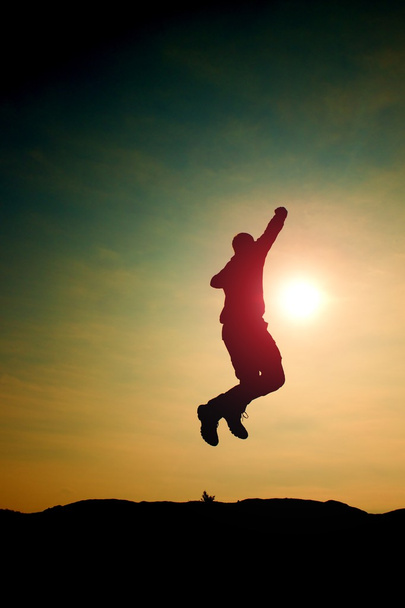 Стрибаюча людина. Молодий божевільний чоловік стрибає на барвистому фоні неба. Силует стрибаючого чоловіка та красиве небо заходу сонця
. - Фото, зображення