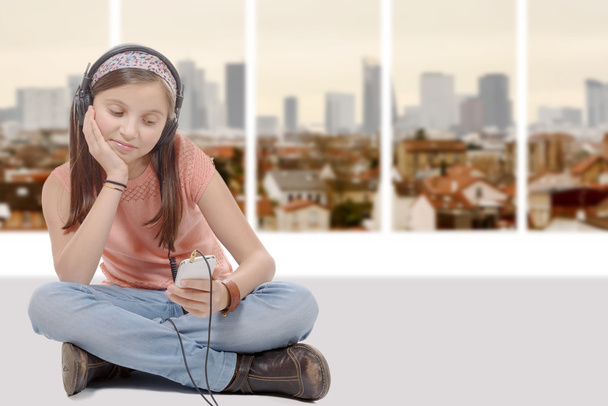 niña preadolescente escuchando música con su teléfono inteligente, cr sentado
 - Foto, Imagen