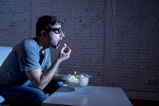  television addict man on sofa watching TV and eating popcorn in funny nerd geek glasses - Фото, зображення
