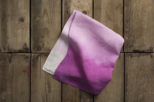 Paño o lino púrpura degradado plegado en la superficie del panel de madera
 - Foto, imagen