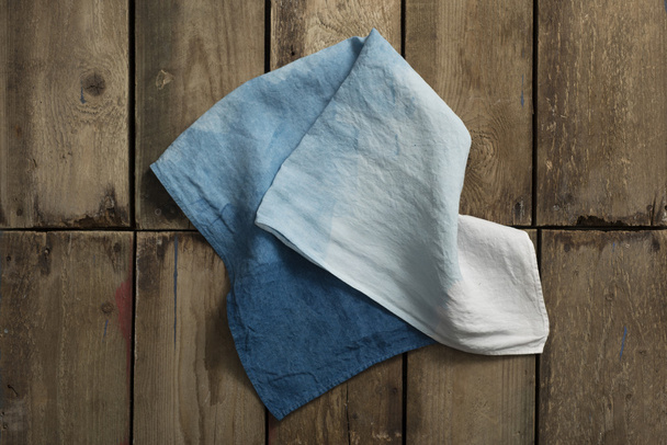 Paño azul degradado plegado o lino en la superficie del panel de madera
 - Foto, imagen