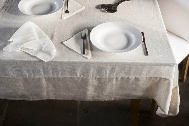 Sets of Dinnerware and Crumpled Napkin on White Linen-Covered Ta - Foto, imagen