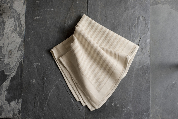 Бежевое полотенце или салфетка на серой каменной поверхности
 - Фото, изображение
