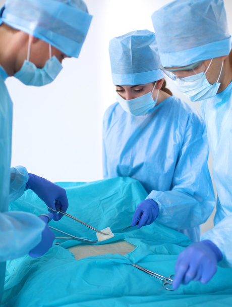 Команда хирурга в форме проводит операцию на пациенте в кардиохирургической клинике
 - Фото, изображение